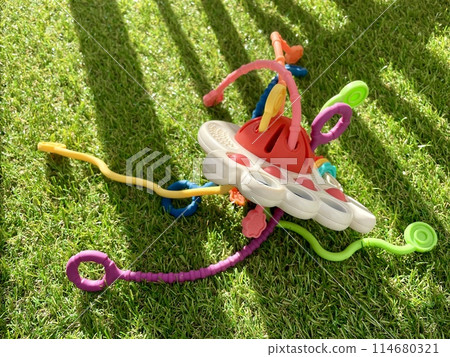 A bright children's toy lies on artificial grass 114680321