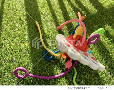 A bright children's toy lies on artificial grass 114680322
