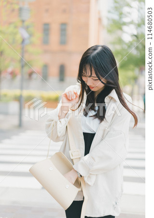 A young woman walking through the city rummaging through her bag because it's a mess and she can't find what she's looking for A young woman walking through the city rummaging through her bag because it's a mess and she can't find what she's looking for 114680503