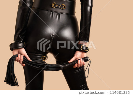 Beautiful dominant mistress woman in latex catsuit posing with riding crop Beautiful dominant mistress woman in latex catsuit posing with riding crop 114681225