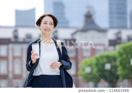 Business woman: A woman walking with a tumbler 114681998