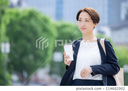 Business woman: A woman walking with a tumbler 114682002