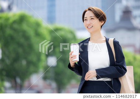 Business woman: A woman walking with a tumbler 114682017