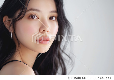 Asian woman with wavy hair, soft makeup, and a gentle expression 114682534