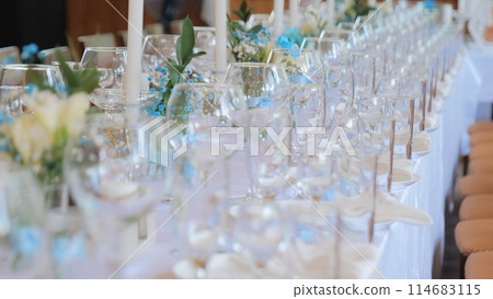Clean and empty sets of four glasses stand next to plates and textile napkins on a banquet table. dining table with glasses and candles. Stylish light table setting, arrangement of dishes. 114683115