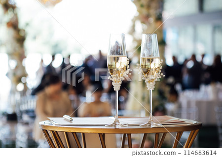 Two wedding glasses stand on a stand against the backdrop of the ceremony arch. Two wedding glasses stand on a stand against the backdrop of the ceremony arch. 114683614