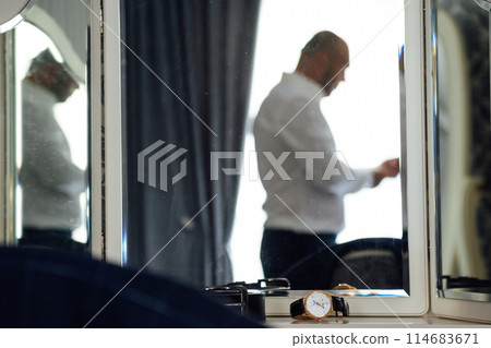 Groom's wedding details. Watch, rings and belt placed on a checkered jacket 114683671