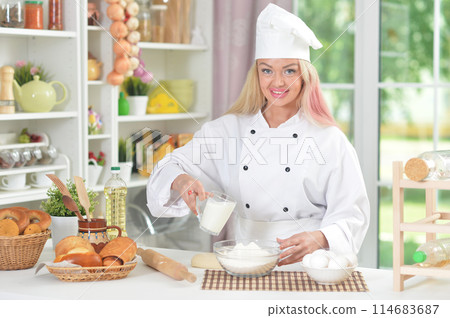 Portrait of beautiful young woman in chefs hat baking at home 114683687