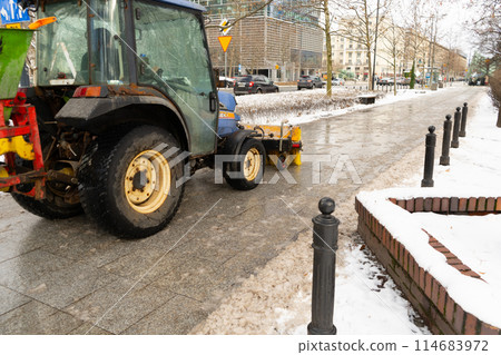 Salting Winter Road Maintenance, Road Salt Mini Tractor Spreader, Snow Plow Truck on Icy Street 114683972