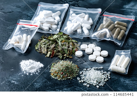 A variety of pills and powders are laid out on a table 114685441