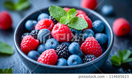 Bowl of mixed berries with large green leaf in the middle 114685623