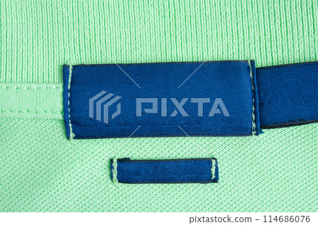 Blank blue laundry care clothes label on green shirt fabric texture background 114686076