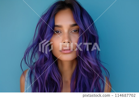 Woman with long, wavy purple hair and a serious expression against a blue background 114687702