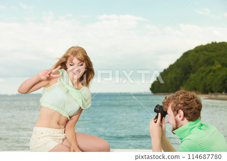 Young couple in love is taking photos on sea pier. 114687780
