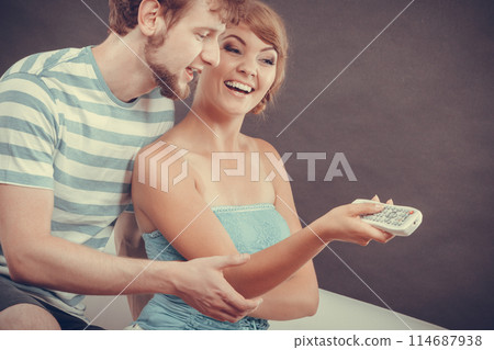 Happy couple on sofa with TV remote 114687938