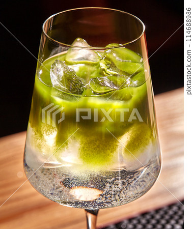 Chilled matcha tonic cocktail in elegant stemmed glass 114688986