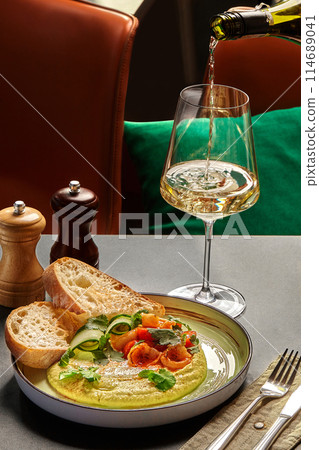 Pouring wine for gourmet hummus with shrimp and greens 114689041