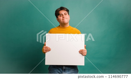 Cheerful man showing blank banner in studio 114690777