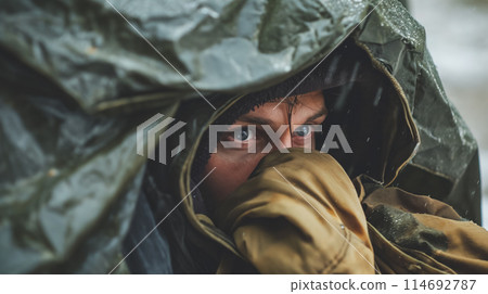 Person with blue eyes under rain poncho. 114692787