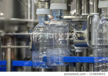 The empty drinking water bottles on the conveyor belt for filling process. The empty drinking water bottles on the conveyor belt for filling process. 114694641