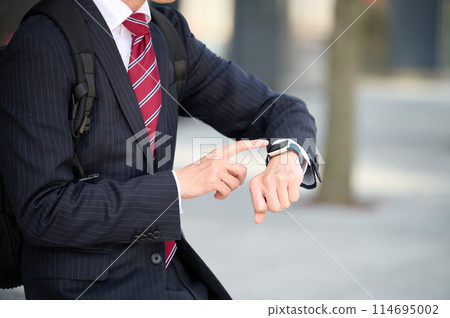 穿著西裝的商人看著智慧手錶 穿著西裝的商人看著智慧手錶 114695002