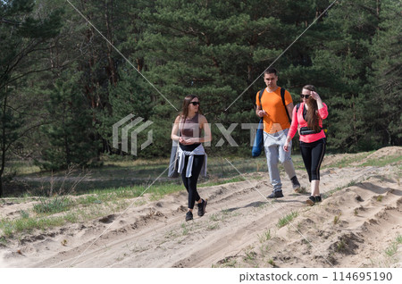Three friends are walking in the forest. 114695190