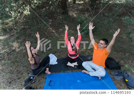 Three friends meditate while sitting in the lotus position in the forest. Three friends meditate while sitting in the lotus position in the forest. 114695193