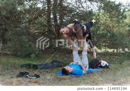 Thre people standing in an elaborate acro yoga pose. Thre people standing in an elaborate acro yoga pose. 114695194
