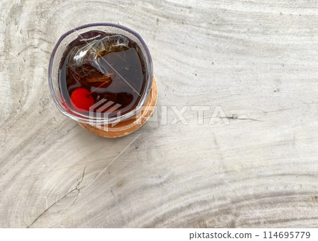 glass with whiskey and ice cube with coctail chery on a grey background top view 114695779
