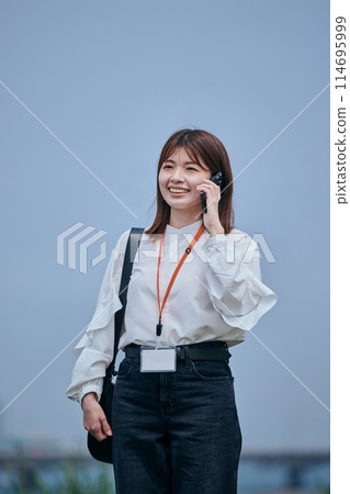 年輕女子邊走邊用智慧型手機說話 114695999