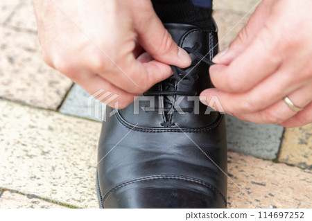 The hands of a businessman tying his untied shoelaces The hands of a businessman tying his untied shoelaces 114697252