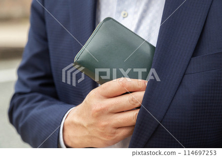 Businessman taking out his wallet from his chest pocket 114697253