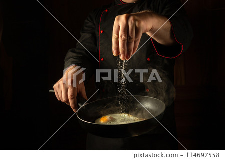 Cooking fried eggs. The chef adds salt to a steaming hot frying pan. Menu idea for a hotel with advertising space. Asian cuisine. Advertising space Cooking fried eggs. The chef adds salt to a steaming hot frying pan. Menu idea for a hotel with advertising space. Asian cuisine. Advertising space 114697558