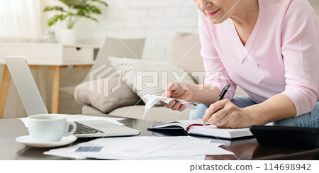 Senior woman bookkeeping bills and payments at home, empty space 114698942