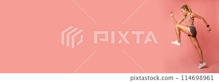 Workout Concept. Determined Fitness Lady Jumping Exercising On Pink Studio Background. Copy Space, Side View, Web-banner Workout Concept. Determined Fitness Lady Jumping Exercising On Pink Studio Background. Copy Space, Side View, Web-banner 114698961