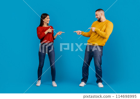 A man and a woman standing facing each other, both pointing accusingly at each other with serious expressions. They seem to be engaged in a heated discussion or argument. A man and a woman standing facing each other, both pointing accusingly at each other with serious expressions. They seem to be engaged in a heated discussion or argument. 114698995