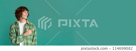 Cool stylish guy with curly hair pointing aside on color studio background, copy space for design, panorama Cool stylish guy with curly hair pointing aside on color studio background, copy space for design, panorama 114699082