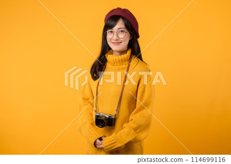 In her cheerful studio, a young Asian woman, wearing a yellow sweater and red beret, snaps pictures with her camera, embracing the joy of photography. 114699116