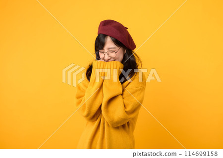 Shy and joyful. A young woman, wearing yellow sweater, red beret, and eyeglasses, shares a moment of surprise against a vibrant yellow background. Shy and joyful. A young woman, wearing yellow sweater, red beret, and eyeglasses, shares a moment of surprise against a vibrant yellow background. 114699158