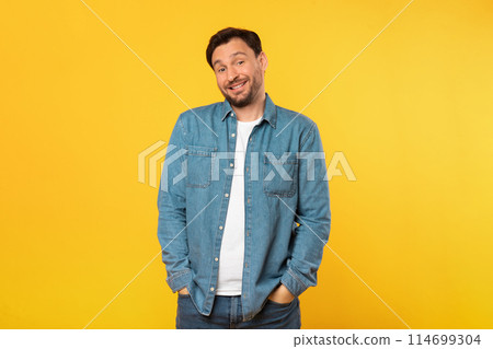 A man is standing upright in front of a vibrant yellow background. He appears confident and focused. The bright color of the backdrop creates a striking contrast with the mans silhouette. 114699304