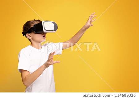 A young boy immersed in virtual reality with a pair of digital glasses on his face. 114699326