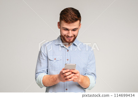 Young man absorbedly text messaging on his cellphone, panorama, free space Young man absorbedly text messaging on his cellphone, panorama, free space 114699434