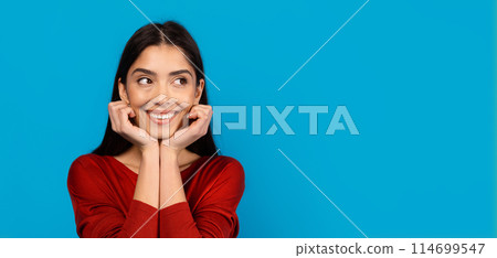 A woman wearing a red shirt strikes a pose while someone takes her picture. She stands confidently, showcasing her stylish outfit, copy space 114699547