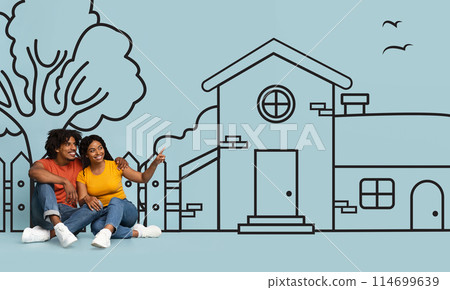 Happy black couple are seated on the ground, facing a detailed drawing of a house. The drawing appears to be on a large sheet of paper laid out on the ground Happy black couple are seated on the ground, facing a detailed drawing of a house. The drawing appears to be on a large sheet of paper laid out on the ground 114699639