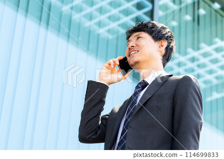 Smiling male businessman talking on a smartphone 114699833