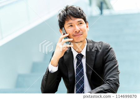 微笑的男性商人在智慧型手機上交談 微笑的男性商人在智慧型手機上交談 114699870
