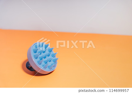 Blue massager for the scalp on an orange background Blue massager for the scalp on an orange background 114699957