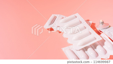 Rectal candles in packaging and ointment in an empty tube on a pink background 114699987