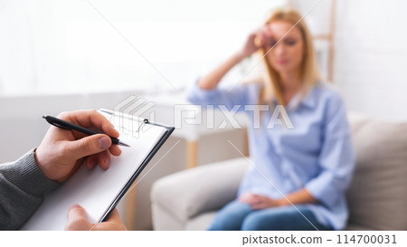 Depressed woman talking to psychotherapist, doctor taking notes about patient's health status, free space Depressed woman talking to psychotherapist, doctor taking notes about patient's health status, free space 114700031