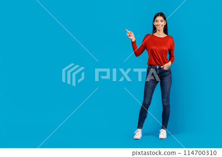 A woman wearing a red shirt is standing and pointing towards an unspecified object or direction. She appears to be gesturing with a sense of urgency or importance, copy space 114700310